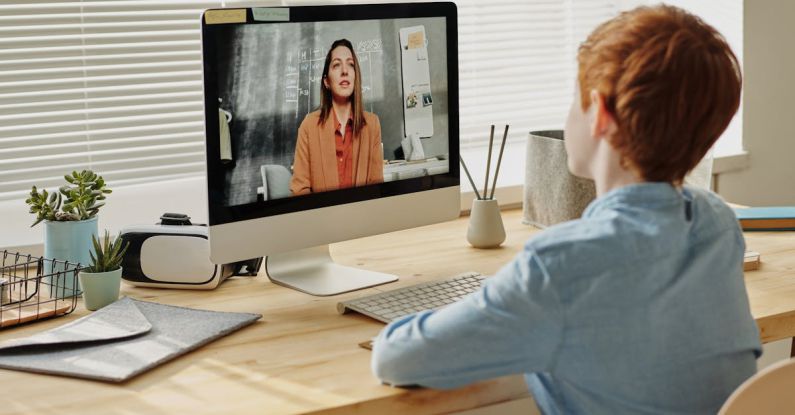 Online Education - Photo of Child Sitting by the Table While Looking at the Imac