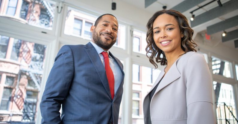 Business Attire - Man and Woman Smiling Inside Building