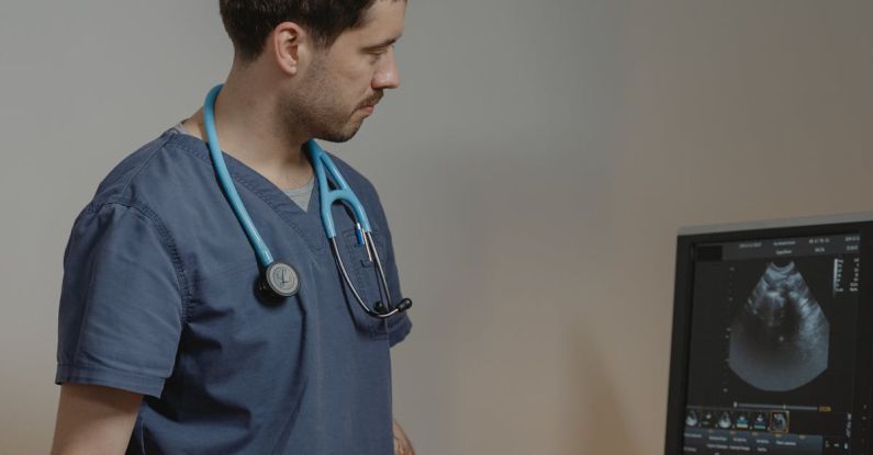 Veterinarian Clinic - Man in Blue Scrub Suit Standing in Front of an Ultrasound Machine