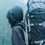 Travel Carrier - Man Wearing Black Hoodie Carries Black and Gray Backpacker Near Trees during Foggy Weather