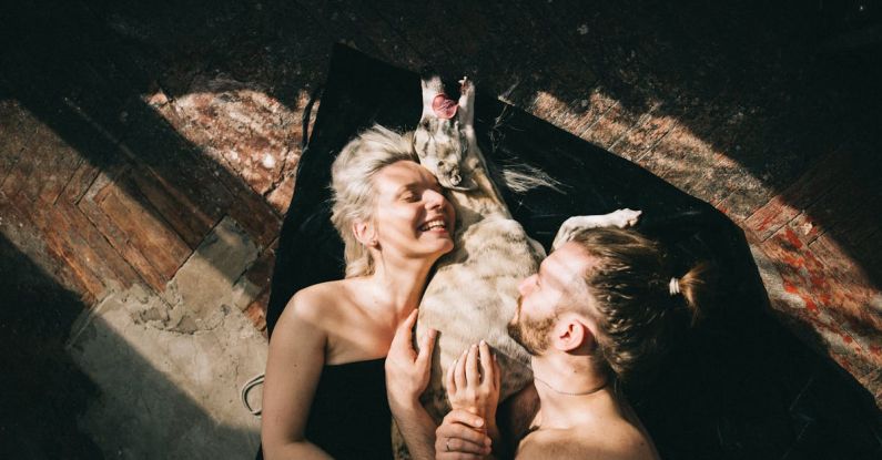 Family Pets - Couple Lying Down and Hugging their Dog