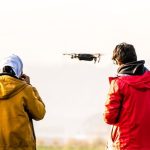 Flying Drone - Two people standing in the grass with a drone