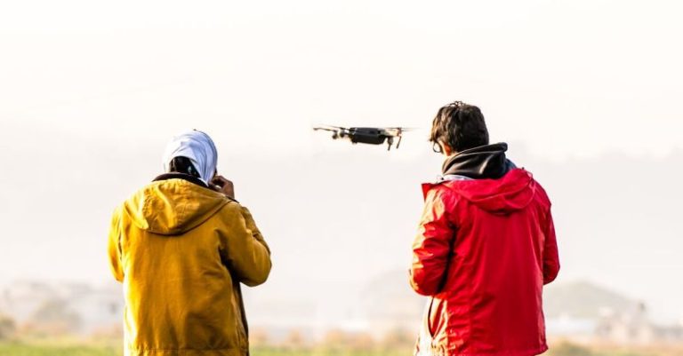 Flying Drone - Two people standing in the grass with a drone
