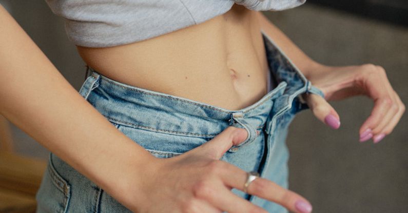 Jeans Fitting - A woman is holding her jeans and looking at her stomach