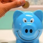Saving Money - Person Putting Coin in a Piggy Bank