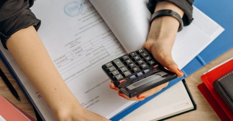 Tax Documents - Person Holding Black Calculator While Using Laptop